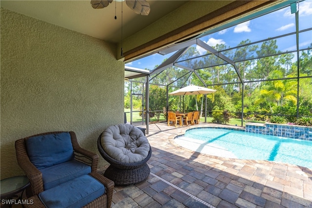 view of pool with a lanai, pool water feature, ceiling fan, and a patio area