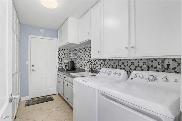 clothes washing area with sink, light tile patterned floors, washing machine and dryer, and cabinets