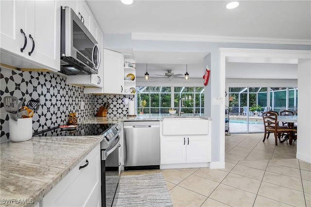 kitchen with sink, backsplash, white cabinets, light stone counters, and stainless steel appliances