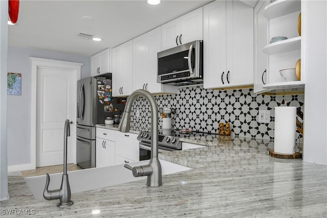 kitchen featuring light stone countertops, backsplash, stainless steel appliances, and white cabinets