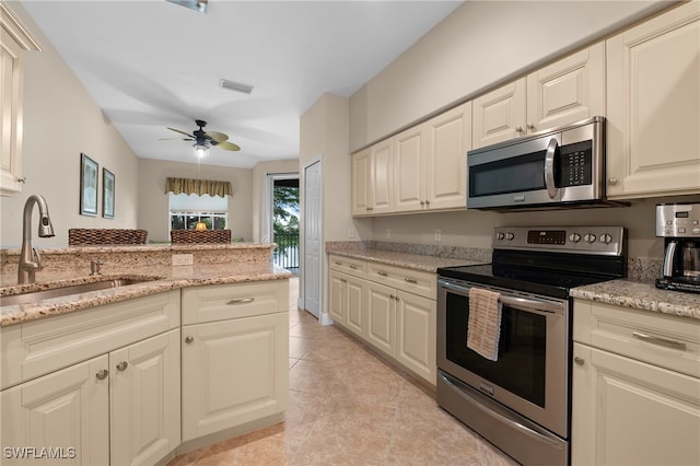 kitchen featuring cream cabinetry, light stone counters, sink, ceiling fan, and appliances with stainless steel finishes