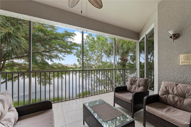 sunroom / solarium featuring ceiling fan and a water view