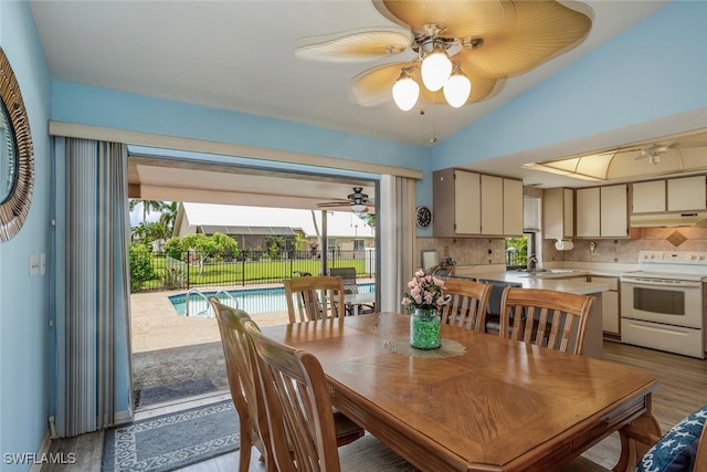 dining area with light wood-type flooring, ceiling fan, and vaulted ceiling