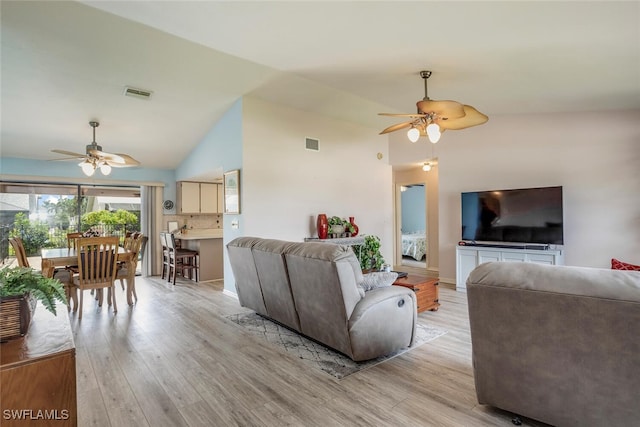 living room with lofted ceiling, ceiling fan, and light hardwood / wood-style floors