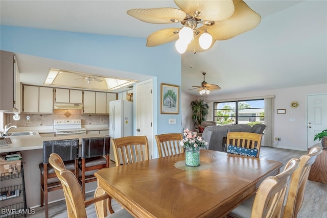 dining area featuring lofted ceiling, light hardwood / wood-style flooring, sink, and ceiling fan