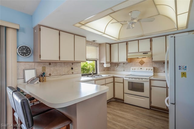 kitchen featuring white appliances, light hardwood / wood-style flooring, kitchen peninsula, sink, and ceiling fan