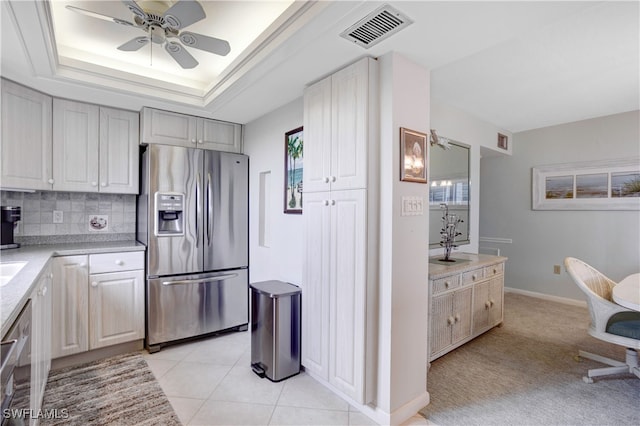 kitchen with tasteful backsplash, light tile patterned floors, stainless steel appliances, a tray ceiling, and ceiling fan