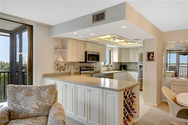 kitchen featuring appliances with stainless steel finishes, plenty of natural light, kitchen peninsula, and decorative backsplash