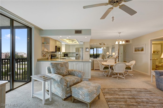 living room with ceiling fan with notable chandelier, sink, and light colored carpet