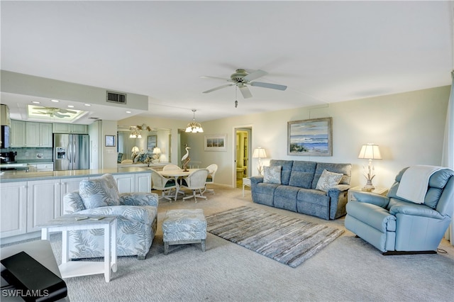 carpeted living room featuring ceiling fan with notable chandelier