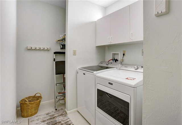 clothes washing area with light tile patterned floors, washing machine and clothes dryer, and cabinets