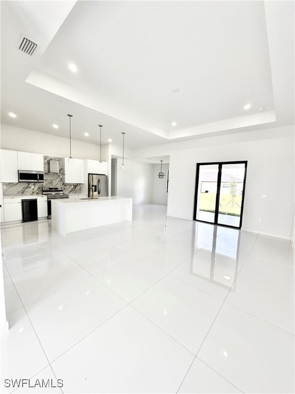 unfurnished living room featuring a raised ceiling and light tile patterned flooring