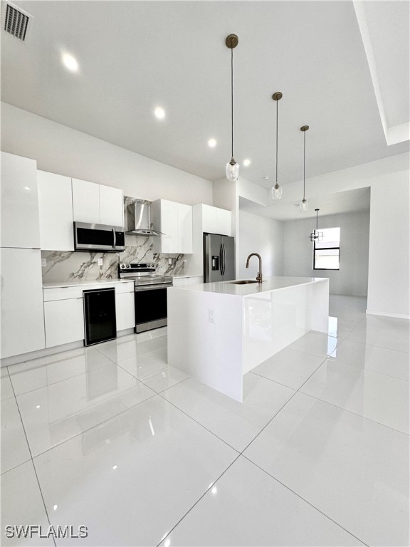 kitchen with pendant lighting, stainless steel appliances, wall chimney exhaust hood, and white cabinetry