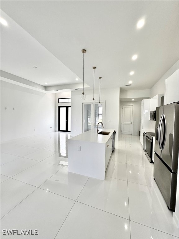 kitchen with pendant lighting, white cabinetry, an island with sink, appliances with stainless steel finishes, and light tile patterned flooring