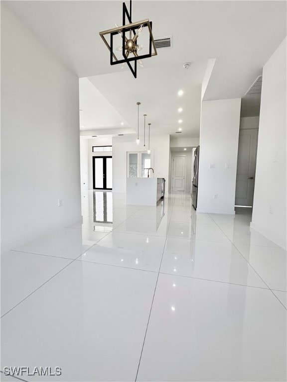 unfurnished room with light tile patterned floors, an inviting chandelier, and sink