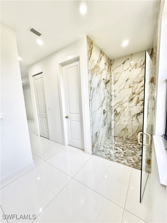 bathroom with a shower with door and tile patterned floors