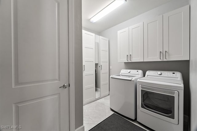 clothes washing area with cabinets and washing machine and dryer