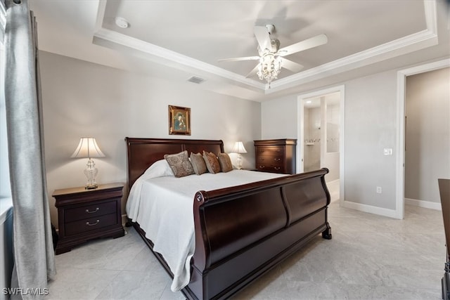 bedroom with ornamental molding, ensuite bath, ceiling fan, and a raised ceiling