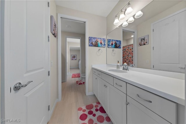 bathroom featuring a shower with shower curtain, wood-type flooring, vanity, and toilet