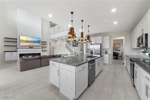 kitchen with appliances with stainless steel finishes, sink, white cabinetry, and an island with sink