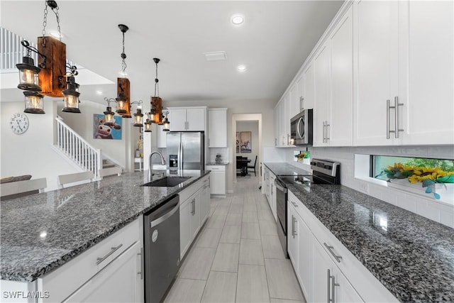 kitchen with stainless steel appliances, a large island with sink, pendant lighting, decorative backsplash, and white cabinets