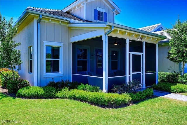 view of side of home with a sunroom, a lawn, and ceiling fan