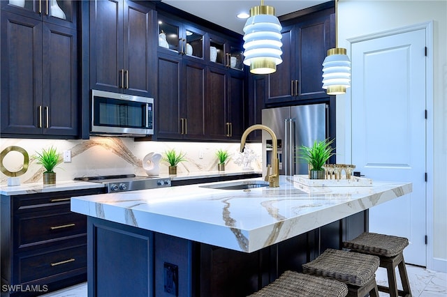 kitchen with stainless steel appliances, sink, a kitchen bar, and an island with sink