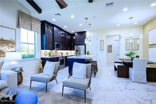 kitchen with appliances with stainless steel finishes, decorative light fixtures, an island with sink, and a breakfast bar area