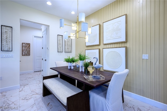 dining area with an inviting chandelier and wooden walls