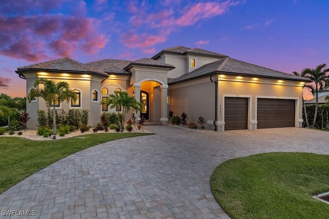 view of front of home with a garage and a lawn