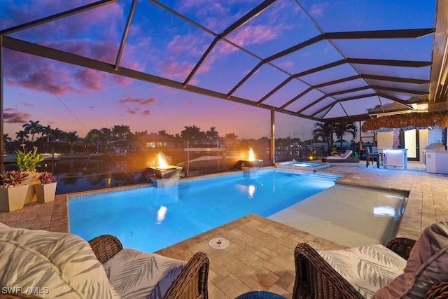 pool at dusk with glass enclosure, an in ground hot tub, and a patio area