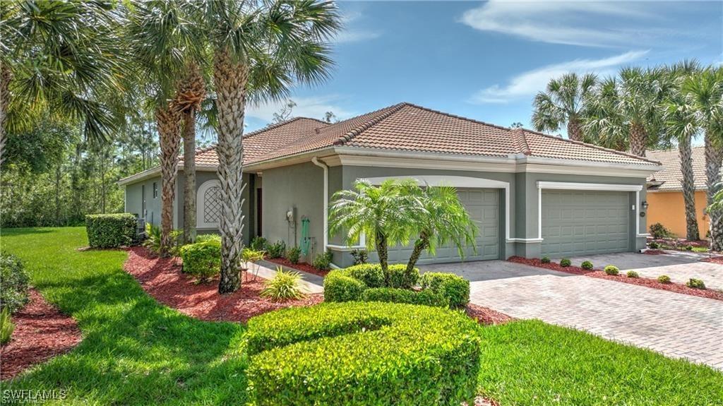 view of front facade featuring an attached garage, stucco siding, a front lawn, a tiled roof, and decorative driveway