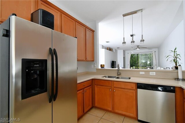 kitchen with hanging light fixtures, light tile patterned floors, appliances with stainless steel finishes, sink, and kitchen peninsula