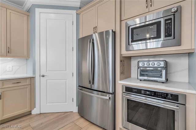 kitchen featuring a toaster, light wood finished floors, stainless steel appliances, tasteful backsplash, and light countertops