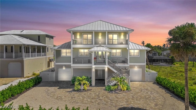 raised beach house featuring an attached garage, a standing seam roof, and metal roof