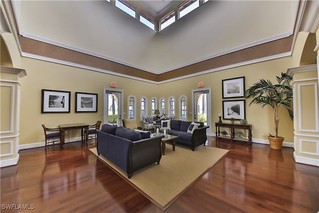 living room featuring ornate columns, dark wood-type flooring, and a high ceiling