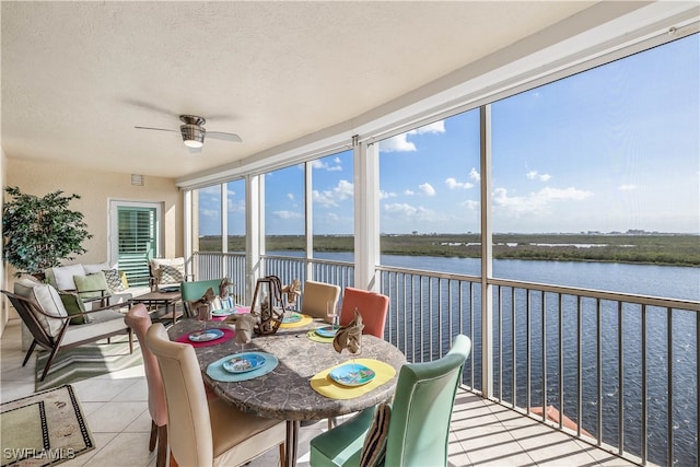 sunroom featuring a water view and ceiling fan