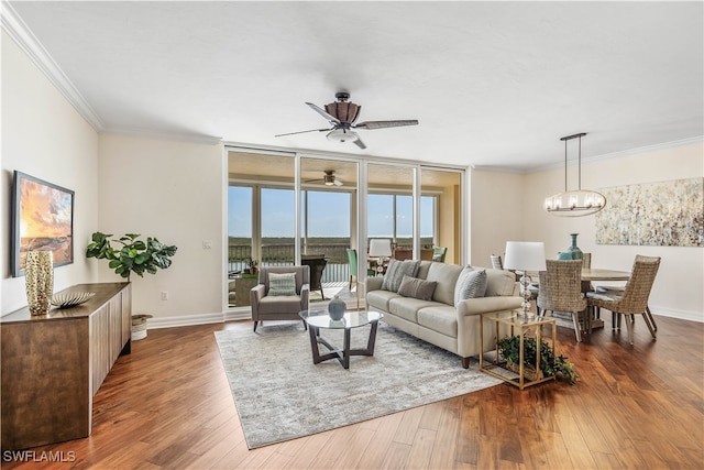 living room with floor to ceiling windows, crown molding, dark wood-type flooring, and ceiling fan with notable chandelier