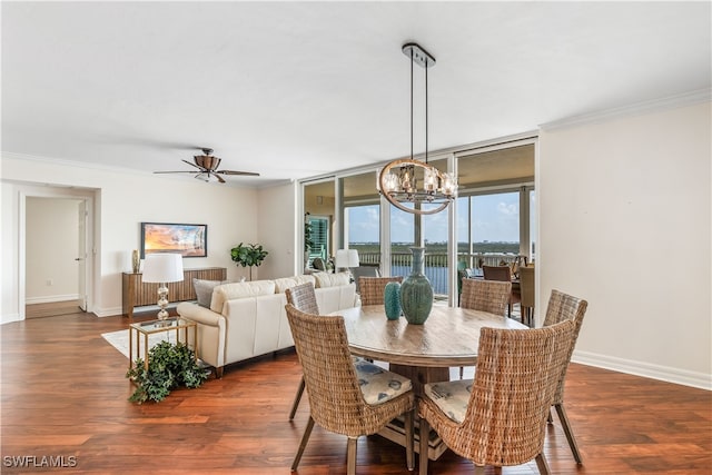 dining area with dark wood-type flooring, crown molding, expansive windows, and ceiling fan with notable chandelier