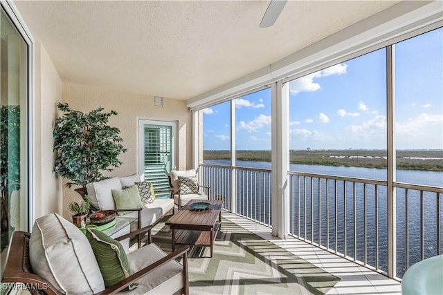 sunroom featuring a water view and ceiling fan