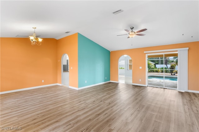 spare room with light wood-type flooring, vaulted ceiling, and ceiling fan with notable chandelier