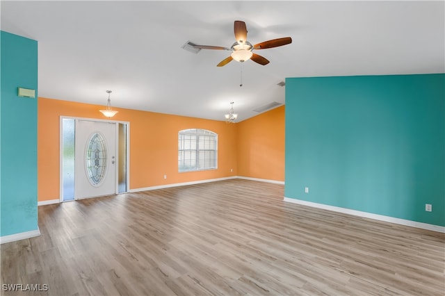 unfurnished living room featuring light hardwood / wood-style flooring, vaulted ceiling, and ceiling fan with notable chandelier