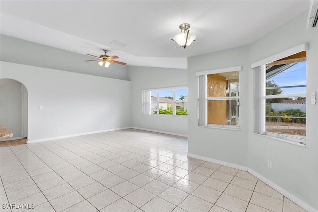 empty room featuring vaulted ceiling, light tile patterned floors, and ceiling fan