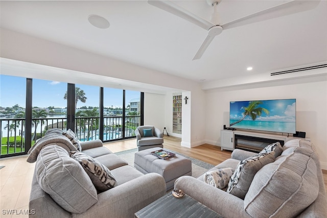 living room featuring a water view, light hardwood / wood-style flooring, and ceiling fan