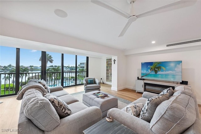 living room featuring a ceiling fan, light wood-type flooring, and baseboards