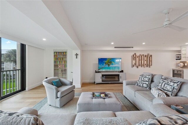 living room featuring a wealth of natural light, ceiling fan, wine cooler, and light wood-type flooring