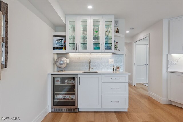 bar featuring white cabinetry, beverage cooler, sink, and light hardwood / wood-style floors