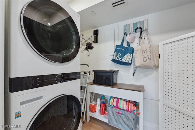 laundry room with stacked washing maching and dryer and wood-type flooring