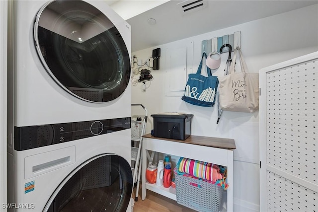 laundry room with visible vents, laundry area, wood finished floors, and stacked washer and dryer