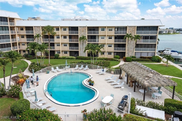 pool featuring a patio area, a water view, and fence